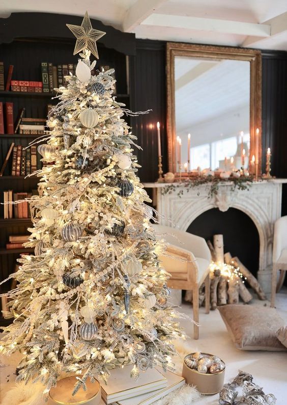 a pretty winter wonderland Christmas space with a flocked Christmas tree with lights, faux fur stockings and a stool, mini houses on the mantel