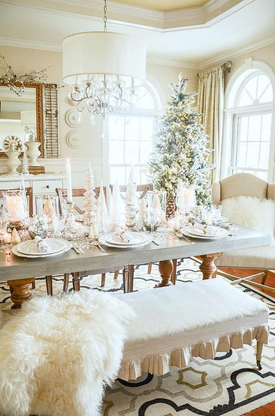 a winter wonderland Christmas table with pillar candles, bottle brush trees, faux snow and cool white porcelain and silver cutlery