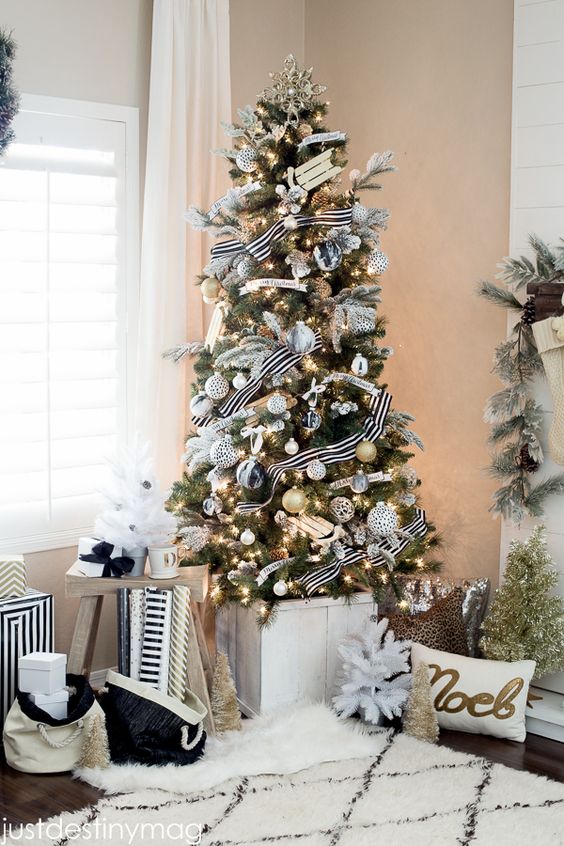 an elegant modern flocked Christmas tree with white, silver and black striped ornaments plus gift boxes is cool