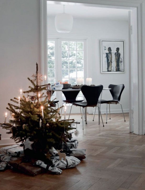 a modern Christmas tree decorated with only red and white ornaments of various looks and shapes, packed gifts and a black and white printed pillow for a modern or Scandi space