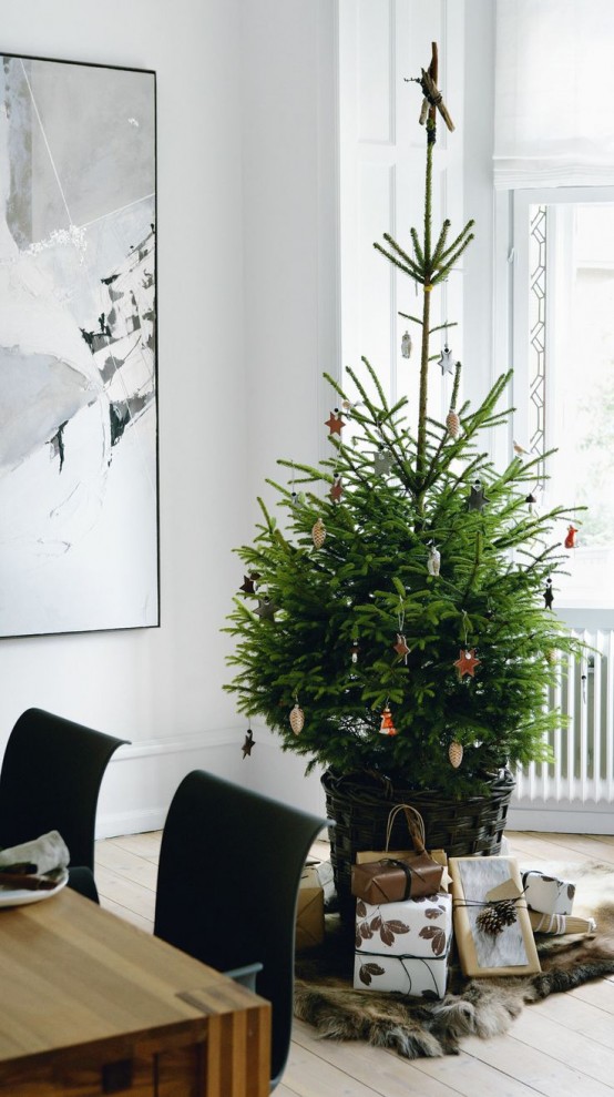 a modern Christmas tree in a basket, with lights, black, white and copper ornaments is a simple and cool idea for a modern space